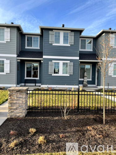 A modern two-story house with a black metal fence in front.