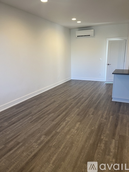 A room with a wooden floor and a white wall with a door.