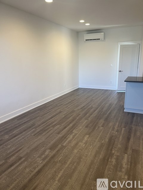 A room with a wooden floor and a white wall with a door.