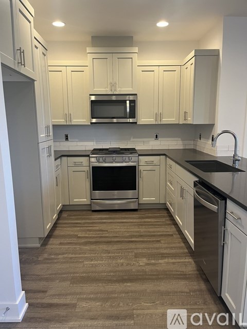 A kitchen with white cabinets and a black countertop.