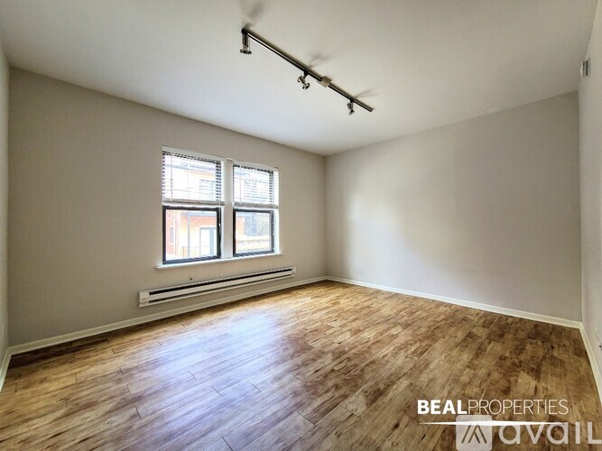 A room with wooden floors and a window with blinds.
