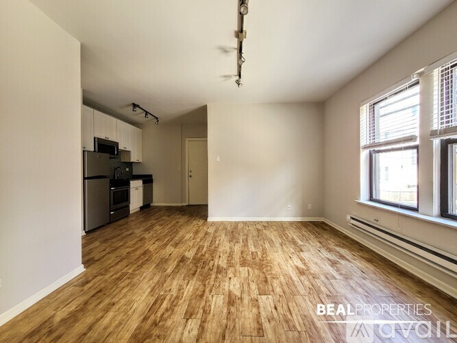 A room with wooden flooring and a window on the right side.
