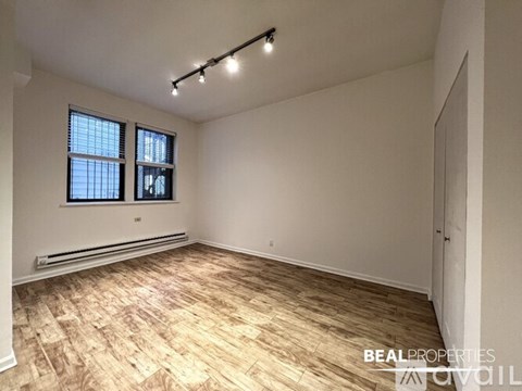 A room with wooden flooring and a window with blinds.
