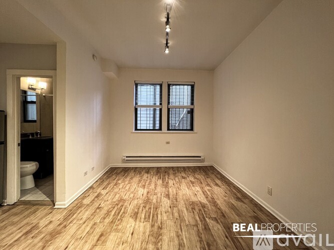 A room with wooden flooring and a window with blinds.