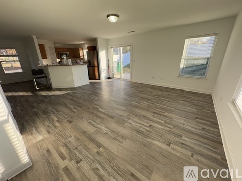 A spacious living room with wooden flooring and a large window.
