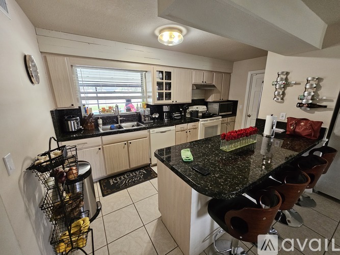 A kitchen with a black granite countertop and wooden cabinets.
