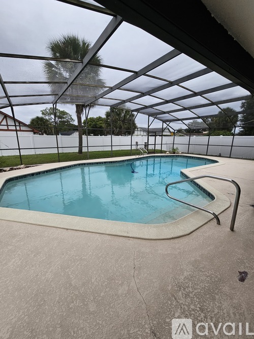A pool under a glass roof with a metal railing.