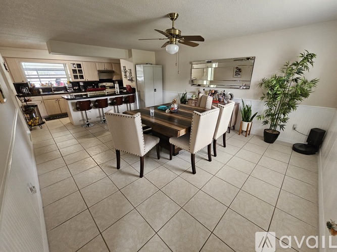 A dining room with a table set for four and a kitchen in the background.