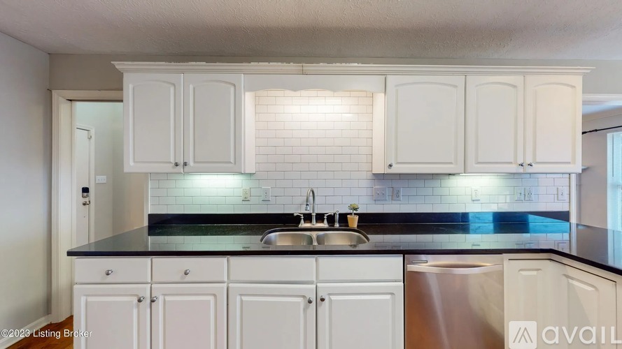 A kitchen with white cabinets and a black countertop.