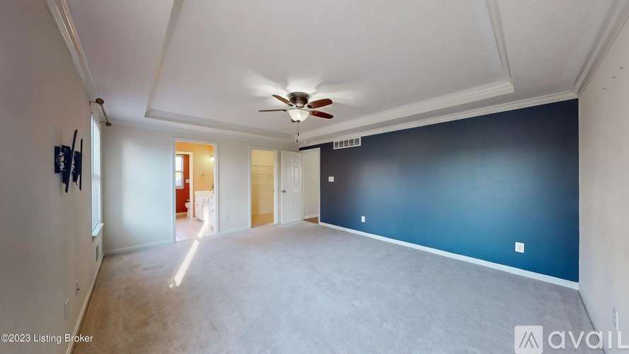 A spacious room with a ceiling fan and a doorway leading to another room.