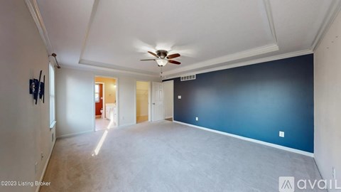 A spacious room with a ceiling fan and a doorway leading to another room.