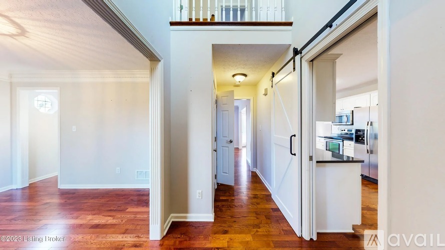 A spacious living room with hardwood floors and white walls.