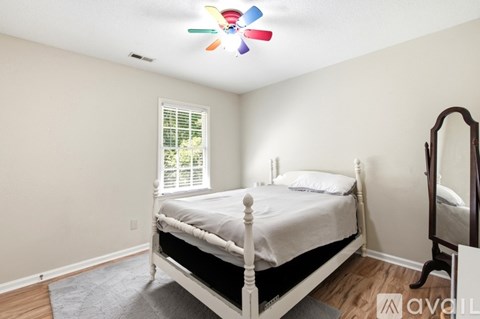 A bedroom with a white bed and a ceiling fan.