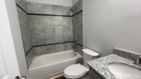 A bathroom with a marble countertop and a glass shower stall.