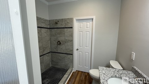 A white door is in a bathroom with a toilet and a shower.