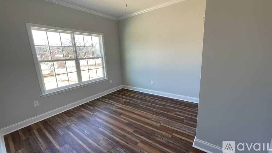 A room with wooden flooring and a large window.