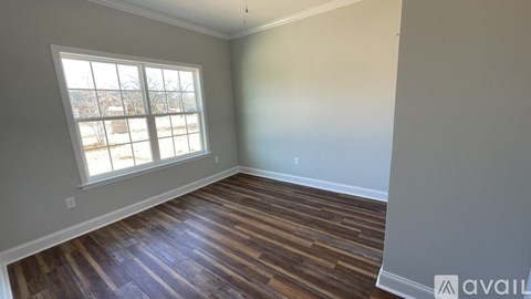 A room with wooden flooring and a large window.