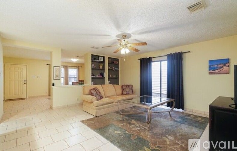 A living room with a couch, a coffee table, and a ceiling fan.