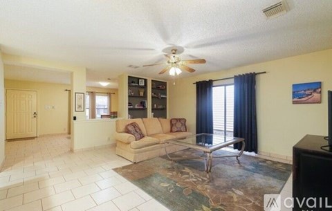 A living room with a couch, a coffee table, and a ceiling fan.