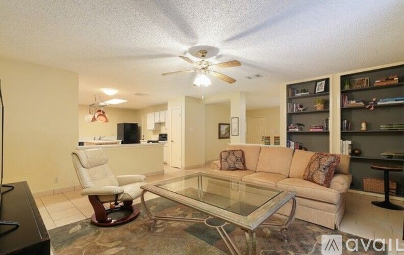 A living room with a glass coffee table and a white chair.