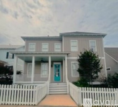 A house with a blue front door and white fence.