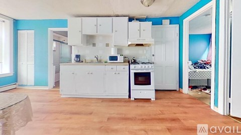 A kitchen with white cabinets and a wooden floor.
