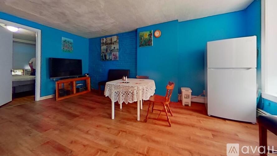 A room with blue walls and wooden flooring has a white table and chairs.