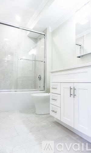 A white bathroom with a glass shower stall and a toilet.