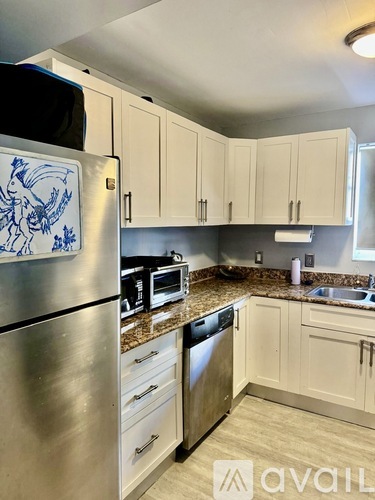 A kitchen with a stainless steel refrigerator and white cabinets.