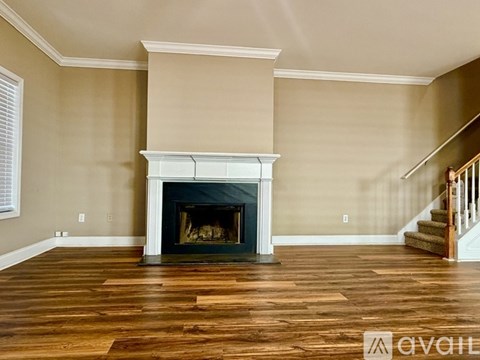 A living room with a fireplace and wooden floors.