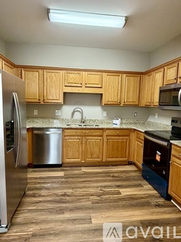 A kitchen with wooden cabinets and a stainless steel refrigerator.