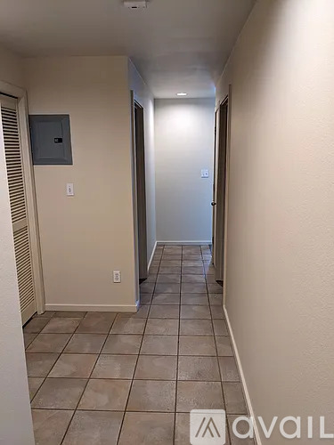 A hallway with tiled floors and a door at the end.