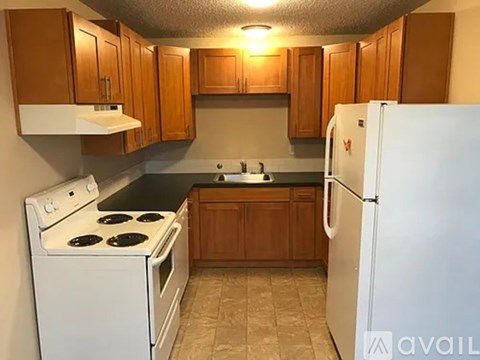 A kitchen with white appliances and wooden cabinets.