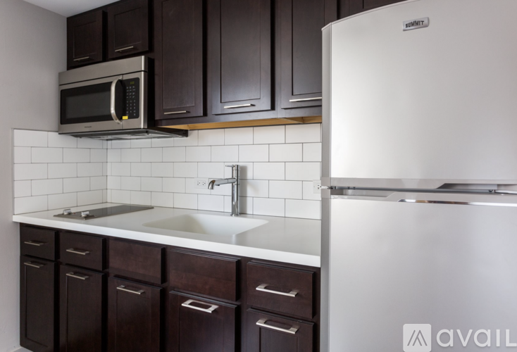 A kitchen with a white refrigerator and a white sink with brown cabinets.