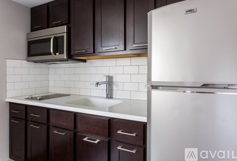 A kitchen with a white refrigerator and a white sink with brown cabinets.