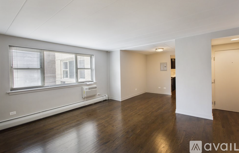 A spacious room with wooden floors and a window with blinds.