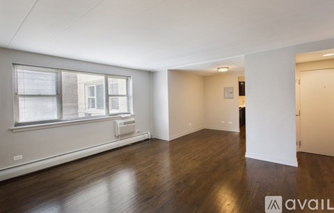 A spacious room with wooden floors and a window with blinds.