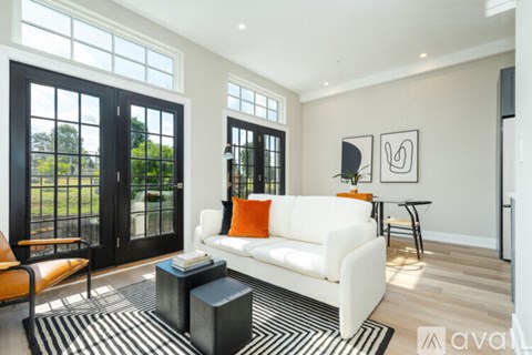 A living room with a white couch and a black and white striped rug.