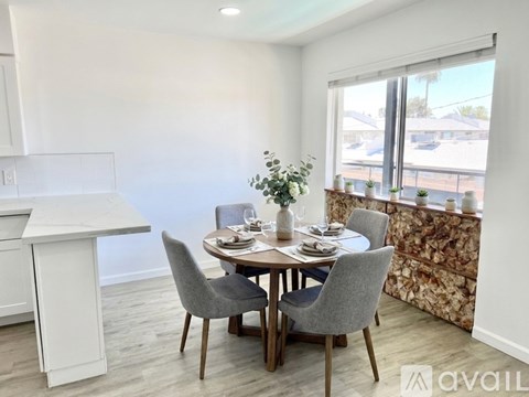 A dining room with a table set for four and a window overlooking a street.