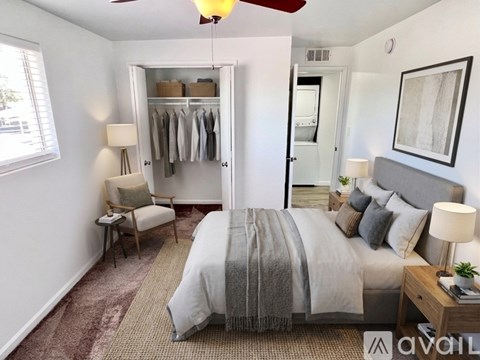 A bedroom with a large bed and a closet with clothes hanging.