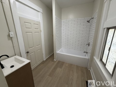 A bathroom with a white door, a white sink, and a white tiled shower.