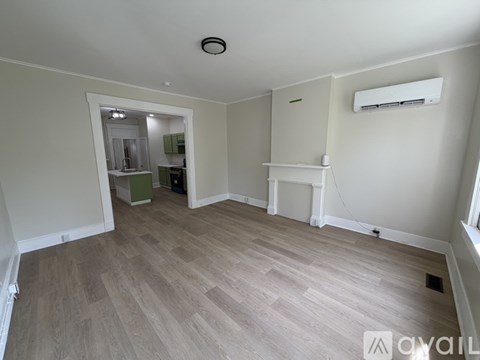 A room with a wooden floor and a white wall with a window.
