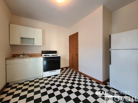 A black and white checkered floor in a kitchen with white cabinets and a black oven.