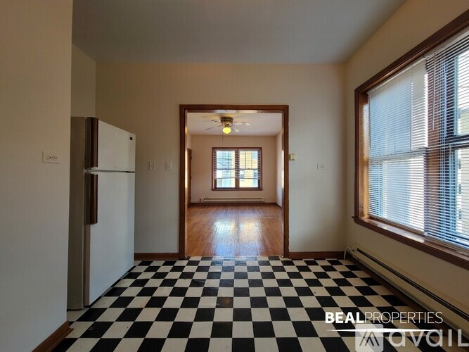 A black and white checkered floor leads to a small room with a window.