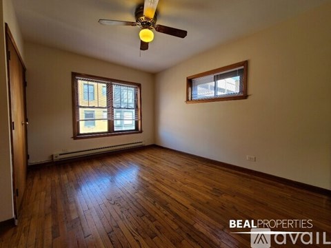 A room with wooden floors and two windows.