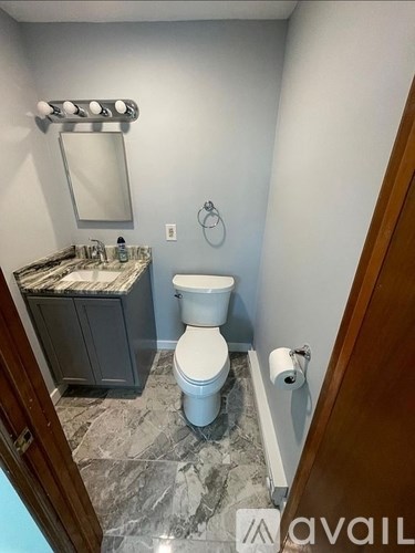 A bathroom with a toilet, sink, and mirror.