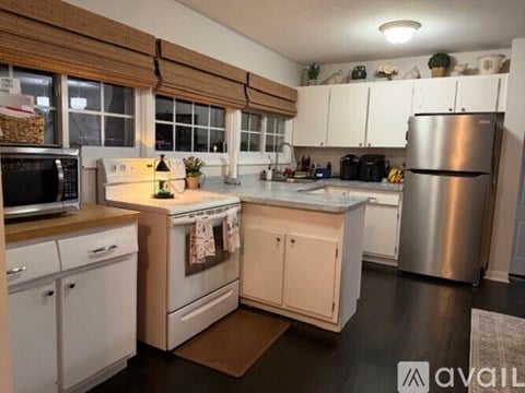 A kitchen with white cabinets and a wooden counter top.