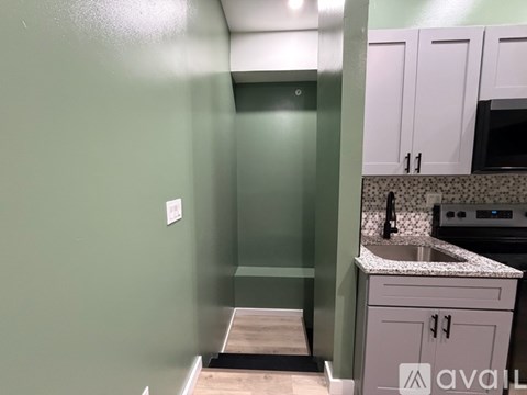 A kitchen with green walls and white cabinets.
