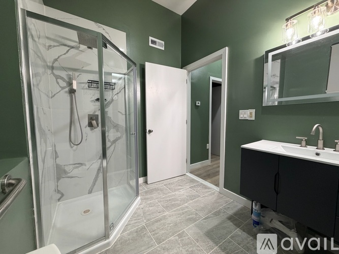 A bathroom with green walls and a glass shower stall.