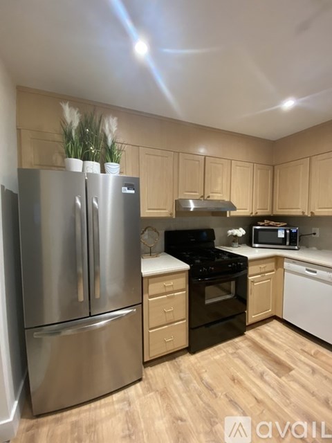 A kitchen with wooden cabinets and a stainless steel refrigerator.